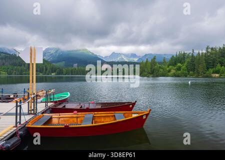 Boote, die auf dem Strbske Pleso See mit der Hohen Tatra in der Slowakei schwimmen Stockfoto