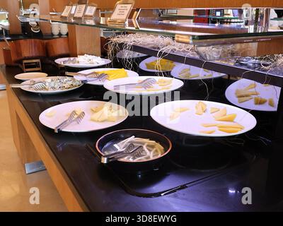 An der Buffetstation des Hotels werden weiße Käsescheiben, Keile und Zangen mit Spiegeln und dekorativen Garnen serviert. Ideal zum Essen und Büfett Stockfoto