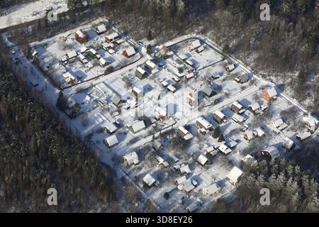 Blick aus der Vogelperspektive auf ein kleines Dorf im Winter. Wohngebiet mit Schnee bedeckt mit Häusern zwischen Bäumen. Winterlandschaft für Reisen und Immobilien Stockfoto