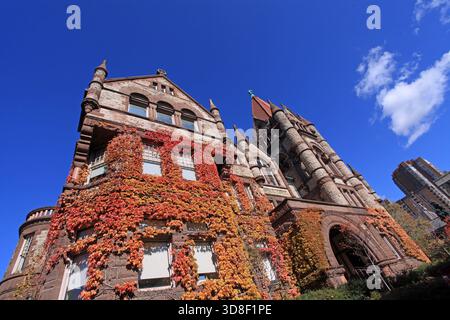 Das Old Vic Gebäude am Victoria College in der University of Toronto, romanische Architektur, erbaut 1891, mit Herbstlaub Stockfoto