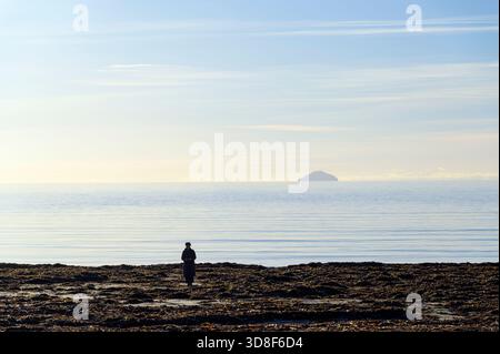 Silhouette einer Frau, die in der Wintersonne am Strand steht, Großbritannien Stockfoto