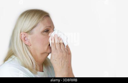 Die Seniorin bläst ihr die Nase. Erkältung oder Grippe Konzept Stockfoto