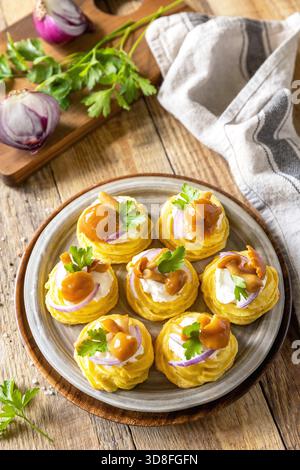 Kartoffeltörtchen gefüllt mit Hüttenkäse und marinierten Pilzen auf einem rustikalen Hintergrund. Stockfoto