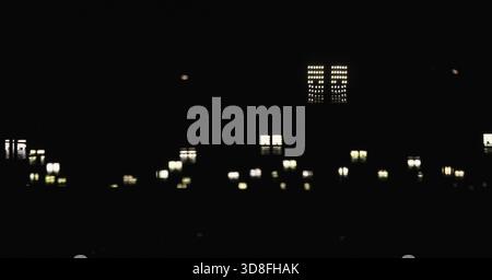 Eine dunkle Skyline mit sanft leuchtenden Straßenlichtern, die einen traumhaften Bokeh-Effekt bilden. Abstrakt und stimmungsvoll, erinnert es an ein ruhiges urbanes Leben und eine ferne Handlung Stockfoto