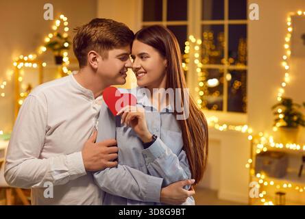 Glückliches Paar umarmt sich mit Red Heart zu Hause Stockfoto