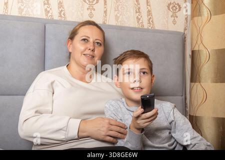 Porträt von glücklicher Mutter und Sohn, die zu Hause fernschauen. Für Themen wie Familienbeziehungen, Unterhaltung im Haushalt und Freizeit. Stockfoto