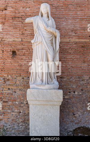 Italien - Rom - Haus der Vestal Jungfrauen - antike Marmorstatue mit Inschrift und drapierten Gewändern an der Backsteinmauer Forum Romanum Stockfoto