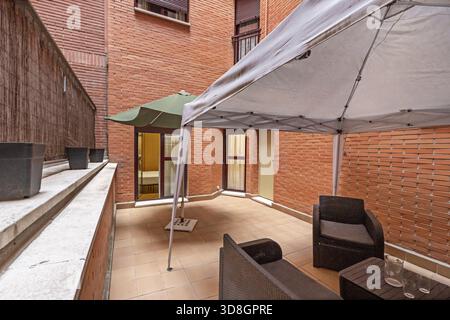 Moderne urbane Terrasse mit Holzfußboden, modularem Sofa im Freien und vertikalem Garten mit integrierter LED-Beleuchtung Stockfoto