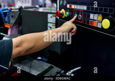 Die Bedienerhand der Maschine schaltet das Bedienfeld der Industriemaschine ein. Taster des Technikers auf dem Bedienfeld Stockfoto