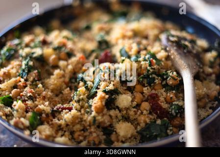 Nahaufnahme einer Schüssel Couscous gemischt mit Spinat, sonnengetrockneten Tomaten und Kichererbsen Stockfoto