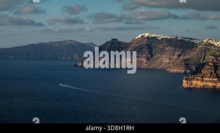 Tiefblaues Wasser füllt Santorinis ausgedehnte Caldera, die von zerklüfteten Bergrücken eingerahmt ist. Stockfoto