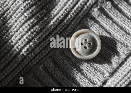 Detailansicht eines Knopfes an einem grauen Strickkleid. Stockfoto