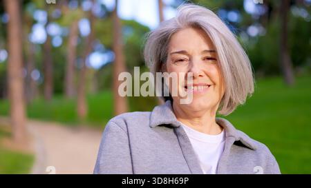 Schöne Seniorin mit grauen Haaren, die draußen lächelt Stockfoto