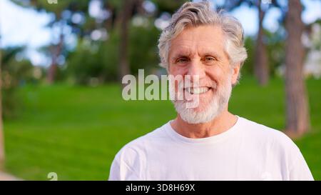 Glücklicher Senior Mann, der draußen in die Kamera lächelt Stockfoto
