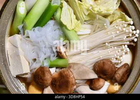 Blick von oben auf japanische Nabe oder Nabemono Suppe mit ungekochtem Chinakohl, Tofu, Enoki und Shitake Pilzen und Shirataki Nudeln Stockfoto