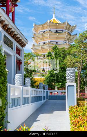 Wunderschöne weiße und goldene Pagode, die durch einen Korridor im chinesischen Stil in Suphanburi gesehen wird Stockfoto
