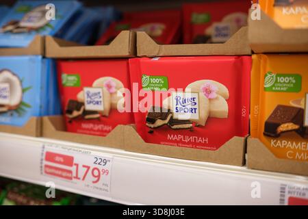 30. November 2025, Moskau, Russland. Hell verpackte Schokoladentafeln sind ordentlich in einem Supermarktregal angeordnet und präsentieren verschiedene Geschmacksrichtungen und Designs Stockfoto