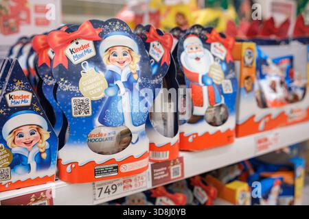 30. November 2025, Moskau, Russland. Farbenfrohe festliche Schokoladenpakete mit Weihnachtsmotiven sind übersichtlich in den Regalen des Lebensmittelgeschäfts angeordnet. Stockfoto