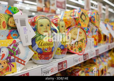 30. November 2025, Moskau, Russland. Hell bemalte russische Puppen in verschiedenen Designs sind ordentlich in einem Ladenregal angeordnet. Stockfoto