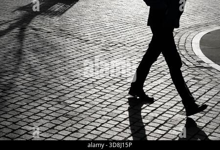 Silhouette eines Mannes, der auf einem Kopfsteinpflasterweg läuft, norfolk, england Stockfoto