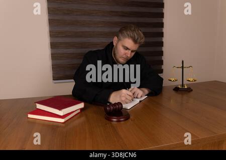 Der Richter prüft die Rechtsdokumente und ein Hammer liegt auf dem Schreibtisch Stockfoto