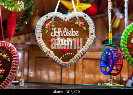 Lebkuchenherz mit der Botschaft Ich liebe dich hängt in einem festlichen Holzstand. Romantisches Lebkuchenherz zu einem traditionellen deutschen weihnachtsfest Stockfoto