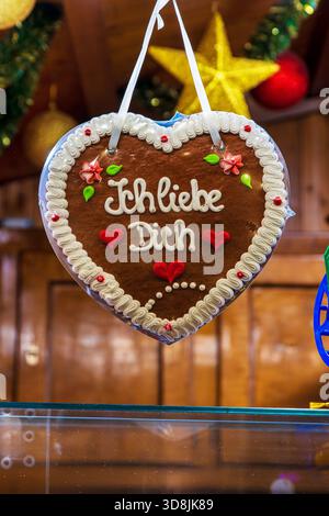 Lebkuchenherz mit der Botschaft Ich liebe dich hängt in einem festlichen Holzstand. Romantisches Lebkuchenherz zu einem traditionellen deutschen weihnachtsfest Stockfoto