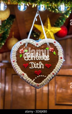 Lebkuchenherz mit der Botschaft Ich liebe dich hängt in einem festlichen Holzstand. Romantisches Lebkuchenherz zu einem traditionellen deutschen weihnachtsfest Stockfoto