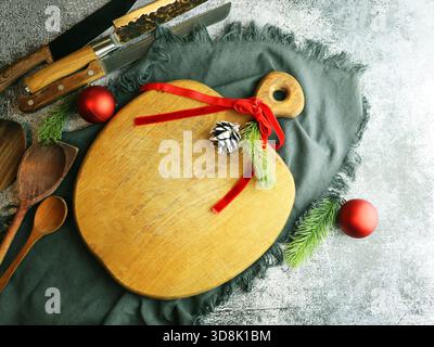 Festliches Schneidebrett aus Holz mit Weihnachtsdekoration und Küchenutensilien Stockfoto