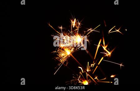 Nahaufnahme einer Gruppe von mehreren hellen Feuerwerk-Funkeln über Schwarz, Hintergrund für Weihnachten, Hochzeit und Unabhängigkeitstag, niedrige Seitenansicht Stockfoto