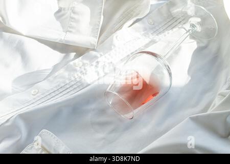 Glas, mit rosafarbenem Wein, verschüttet auf einem weißen Hemd, Nahaufnahme, selektiver Fokus, keine Leute, Konzept, Draufsicht, Stockfoto