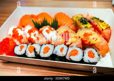 Nahaufnahme eines köstlichen und leckeren japanischen Lachs-Sushi mit fliegendem Fischrogen, Mayonnaise und Käsesauce, serviert auf einem Teller Stockfoto