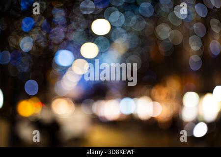 Abstrakter Hintergrund von verschwommenen Stadtlichtern oder Bokeh-Lichtern bei Nacht. Verschwommene Lichterketten, unscharf, keine Leute, Weitwinkel Stockfoto