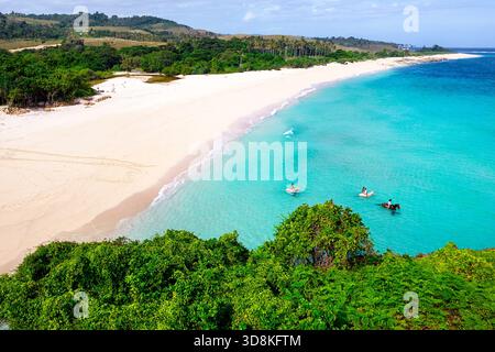 Touristen reiten im Meer am Marosi Strand auf dem südlichen Teil der Insel Sumba, Indonesien, Pferde schwimmen im türkisfarbenen Wasser Stockfoto