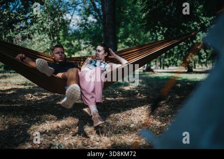 Paare entspannen in einer Hängematte im Park an einem sonnigen Tag und genießen Freizeit im Freien Stockfoto