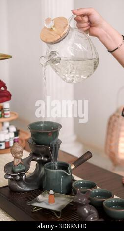 Flüssiges Ausgießen. Teezeit. Frau Hände füllen Glas Teekanne mit trinken erfrischendes Wasser gesunde Lebensweise Weihrauch brennen. Stockfoto