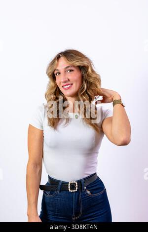 Lächelnde junge Frau, die ein weißes T-Shirt und Jeans trägt und in die Kamera blickt Stockfoto
