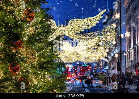 Weihnachtsdekoration im Zentrum von London, England, während der Nacht mit verschwommenem Straßenverkehr und Feenlichtern von einem Baum Stockfoto