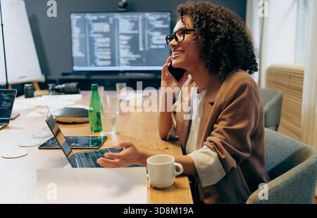 Frau, die den Code überprüft, während sie Kaffee trinkt, Einzelperson analysiert die Programmierung auf dem Computerbildschirm Stockfoto