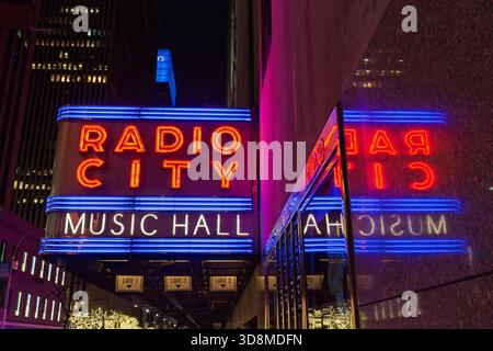 Das Neonschild der Radio City Music Hall spiegelt sich in der Wand des Rockefeller Center. Stockfoto