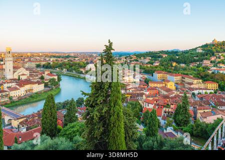 Panoramablick auf die Altstadt von Verona mit Fluss Etsch, Terrakotta-Dächern, Zypressen, Kathedrale von Verona und farbenfrohen Gebäuden bei Sonnenuntergang Stockfoto