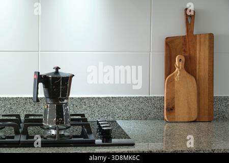 Mokakanne, die Kaffee auf einem Gasherd in einer Küche mit hölzernen Schneidebrettern zubereitet Stockfoto