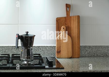 Mokakanne, die Kaffee auf einem Gasherd in einer Küche mit hölzernen Schneidebrettern zubereitet Stockfoto