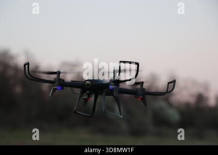 Drohne fliegt bei Sonnenuntergang – Quadcopter-Silhouette im Abendhimmel. Quadcopter Drohne im Flug während der Dämmerung mit Soft Cloud Stockfoto