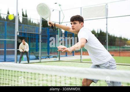 Sportlicher junger Mann, der auf dem Platz Padel spielt Stockfoto