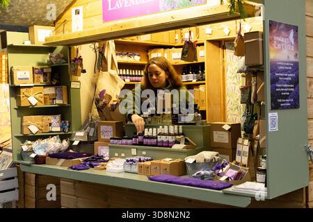 Eine Frau arrangiert Lavendelprodukte an einem Stand der Somerset Lavender Farm und bietet natürliche, handgemachte Artikel an. Stockfoto