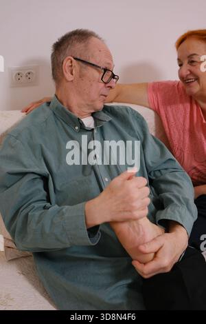 Seniorenpaare, die zu Hause trainieren, an Knie-, Knöchel- oder Handgelenkverletzungen leiden. Geben Sie eine Fußmassage für einen Mann und eine Frau, ein älteres Paar Stockfoto