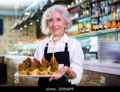 VIW über die europäische alte Dame, die Tapas in einem Pub hält Stockfoto