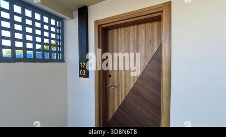 Eine hölzerne Hotelzimmertür mit der Zimmernummer 1203, eingerahmt von warmer Flurbeleuchtung. Stockfoto