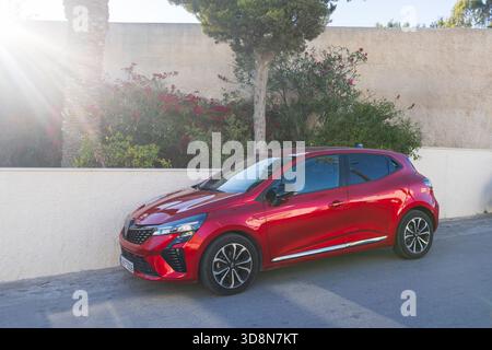 Roter Renault Clio Fließheck, der am 5. Oktober 2025 auf einer sonnigen Straße in Santorin, Griechenland, geparkt wurde Stockfoto
